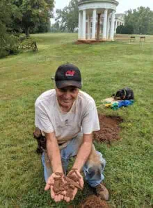metal detectorist with artifacts from blacksmith shop excavations