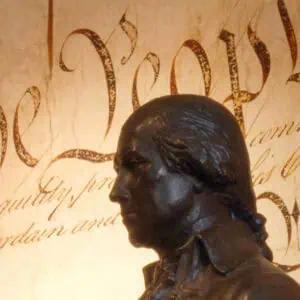 Bronze statue of James Madison in front of a large display of the U.S. Constitution’s “We the People” preamble text.